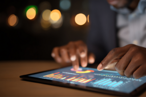 Hände bedienen ein Marketing-Dashboard auf einem Tablet mit Attributions- und Leistungsdaten